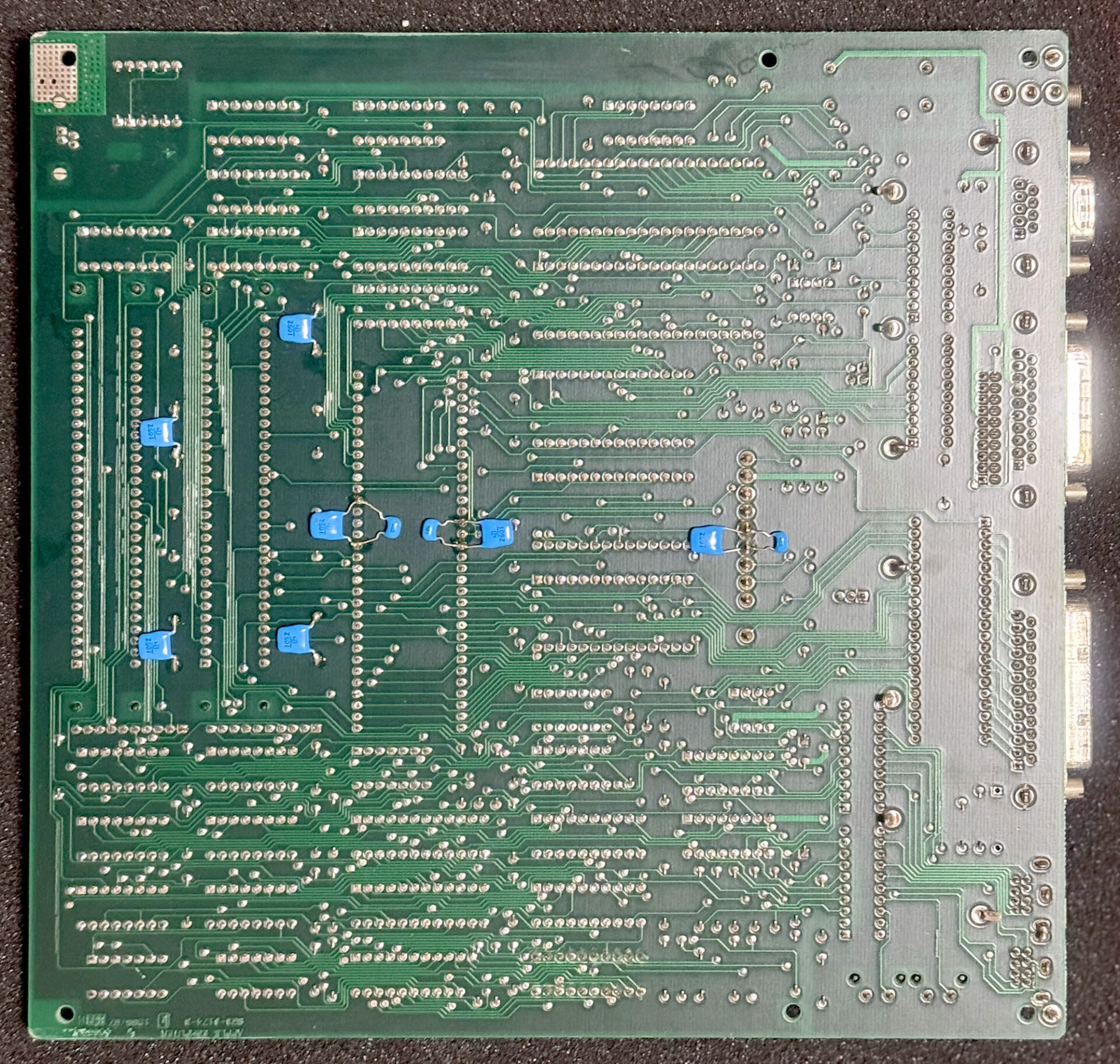 Macintosh Plusのロジックボードうら面には、筆者によってMLCC(水色のコンデンサ部品)が追加されている。取り付け場所はノイズ発生源であるCPUの電源ピン、メモリSIMMの電源部、そしてアナログボードからの電源を受け取るコネクタ部の3カ所。大きいMLCCは1μF(105)、小さい方が0.1μF(104)となっている。同様の処置はアナログボードにも施してある。